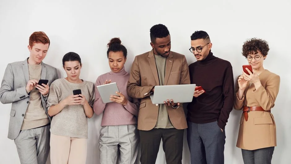 Des mains tenant un smartphone à côté d’un ordinateur portable affichant des graphiques boursiers, illustrant le trading numérique.